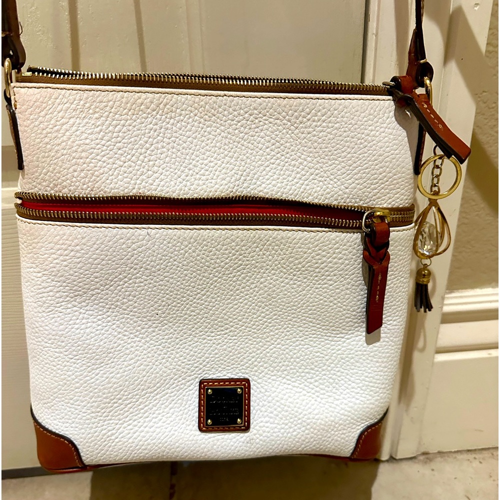 Crossbody bag is made pebbled leather, brown leather trim with red interior.